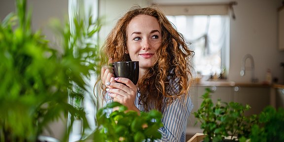 Welcher Tee hilft bei Erkältungen? Rothaarige Frau mit Teetasse in der Hand